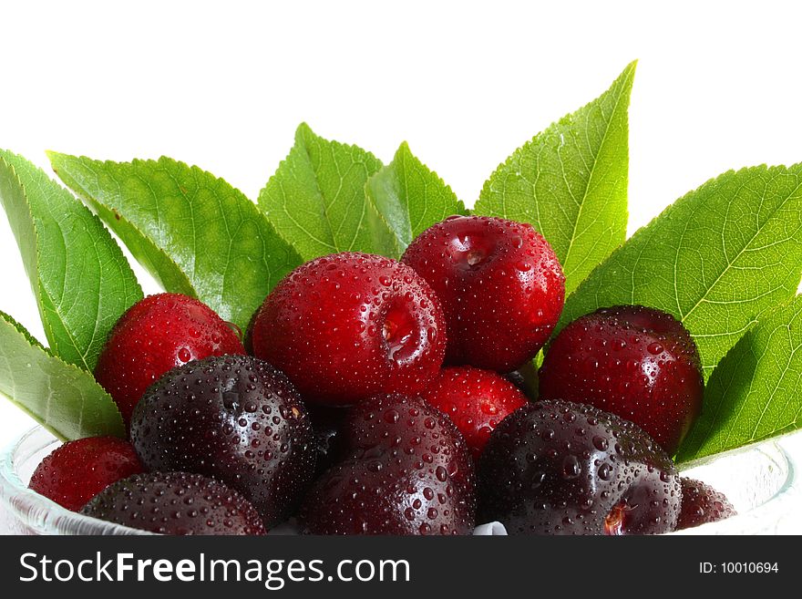 Sweet cherry in a glass, with leaves on a white background, it is isolated.