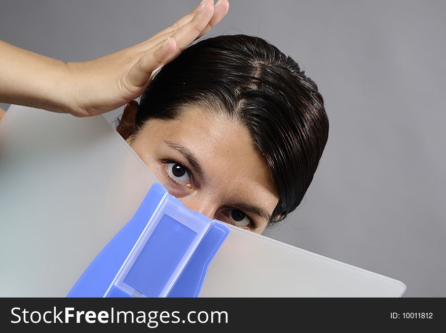 Woman with brown eyes hiding with documents in office