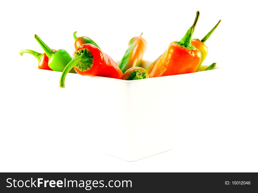 Red and green chillis in a white square bowl with clipping path on a white background. Red and green chillis in a white square bowl with clipping path on a white background