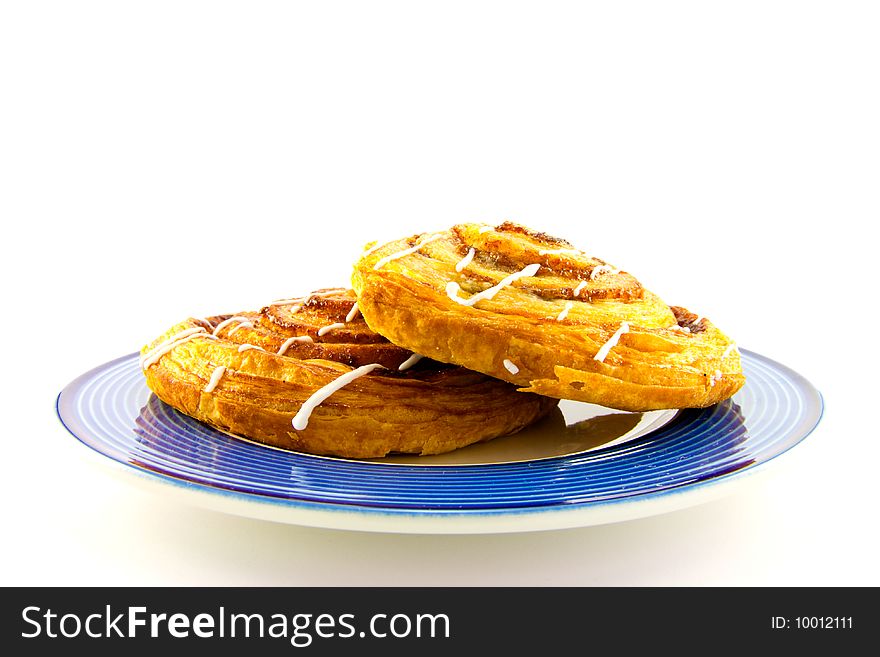 Two cinnamon buns on a blue plate with clipping path on a white background