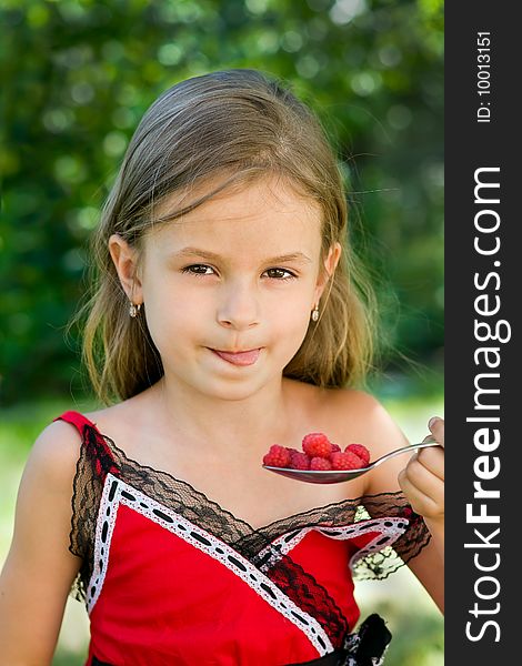 A little girl of 6 years old eating delicious raspberry. A little girl of 6 years old eating delicious raspberry