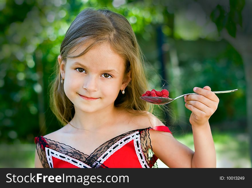 A little girl of 6 years old eating delicious raspberry. A little girl of 6 years old eating delicious raspberry
