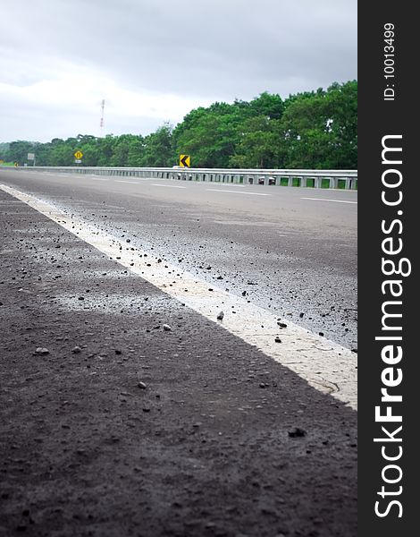 Scenery of an empty toll road in a cool and quiet morning after the rain. selective focus on white road line marking. Scenery of an empty toll road in a cool and quiet morning after the rain. selective focus on white road line marking