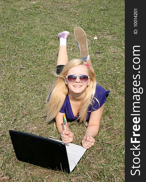 Happy girl with a laptop lying on grass