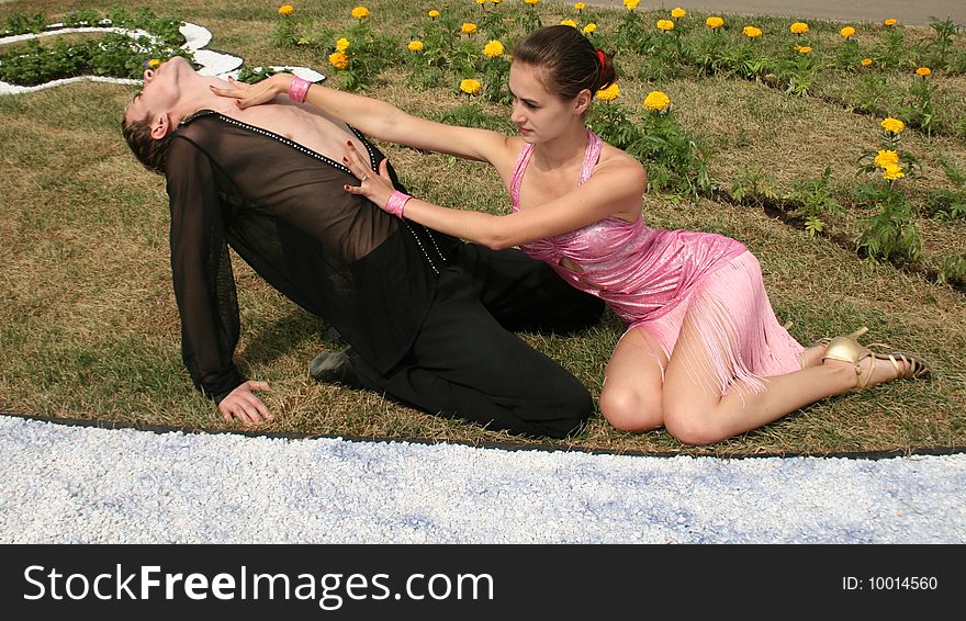 Playful couple sitting among flowers on grass