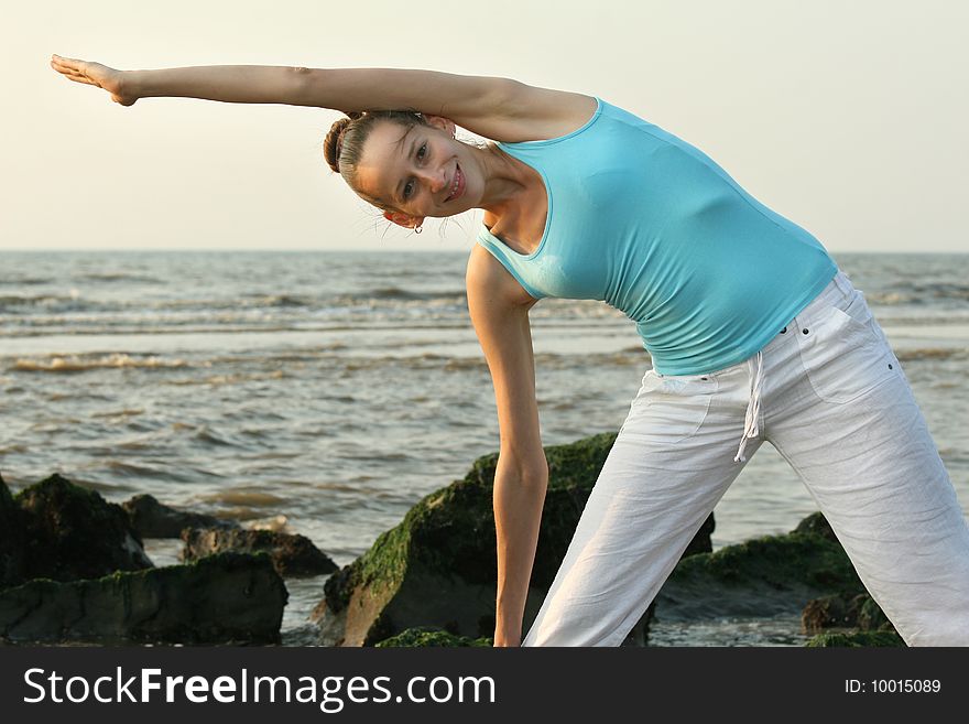 Woman doing yoga workout at the beach by sunset. Woman doing yoga workout at the beach by sunset
