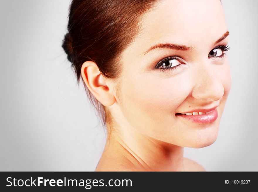 A close up of a beautiful smiling woman in front of a gray background. A close up of a beautiful smiling woman in front of a gray background.