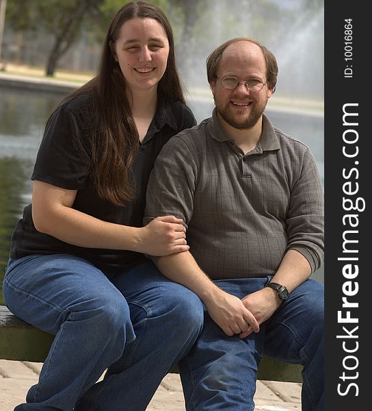 Loving couple sitting down with a fountain going off in the background