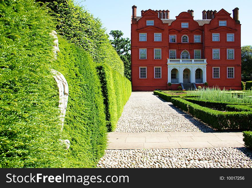 A rear view of Kew palace at Kew gardens England. The picture shows a statue in the hedge.