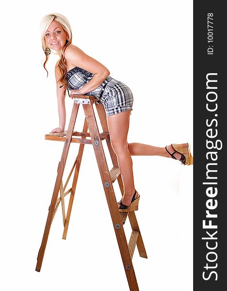 Pretty young girl in a black and white shorts and top with long blond hair standing on the wooden stepladder, holding an red rose in her mouth. Pretty young girl in a black and white shorts and top with long blond hair standing on the wooden stepladder, holding an red rose in her mouth.