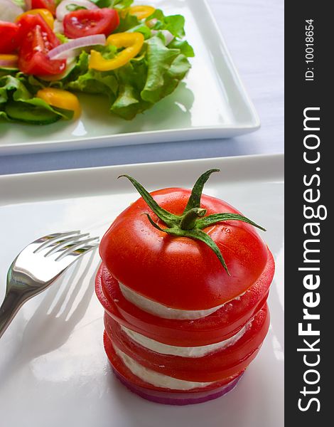 Layered tomato with salad in background. Layered tomato with salad in background