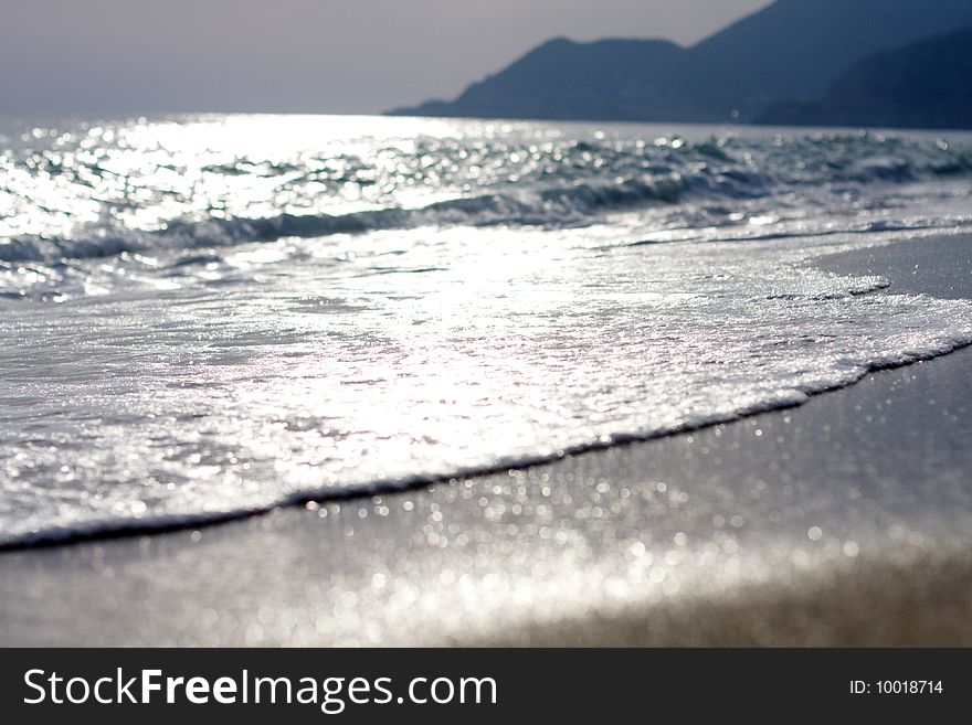 Wave running on sandy coast of the Mediterranean sea on a decline