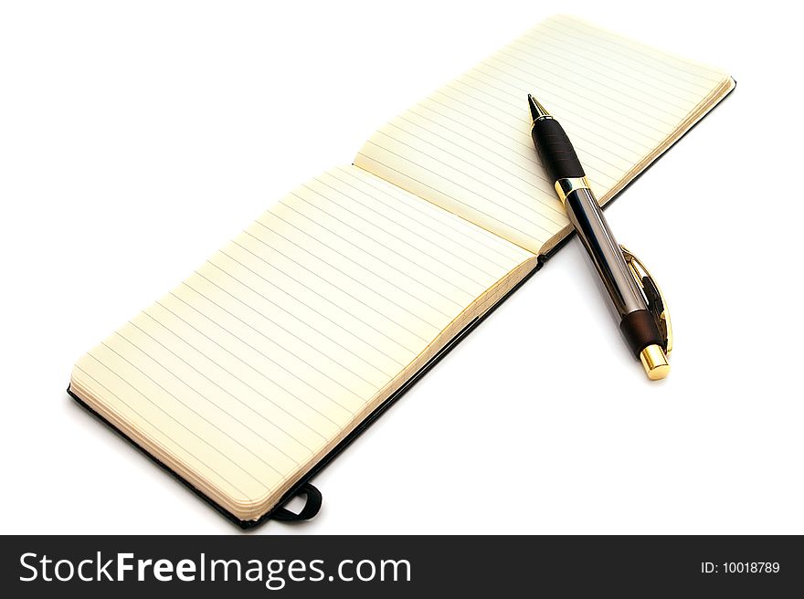 A fancy expensive pen is resting on an open old fashioned lined note pad with blank pages and slightly yellowed edges on white. A fancy expensive pen is resting on an open old fashioned lined note pad with blank pages and slightly yellowed edges on white