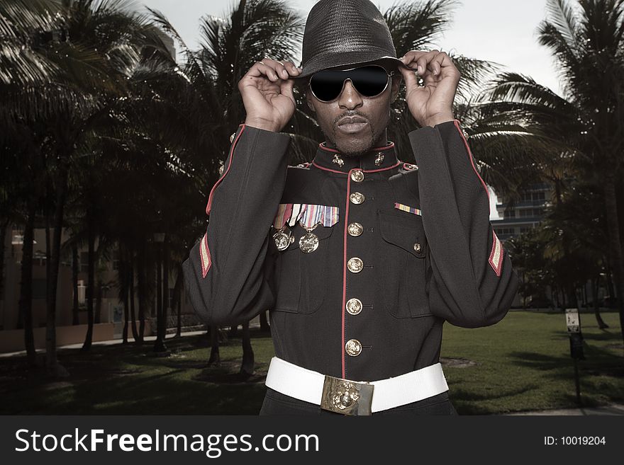 Fashionable model wearing a military jacket with a hat and sunglasses. Fashionable model wearing a military jacket with a hat and sunglasses