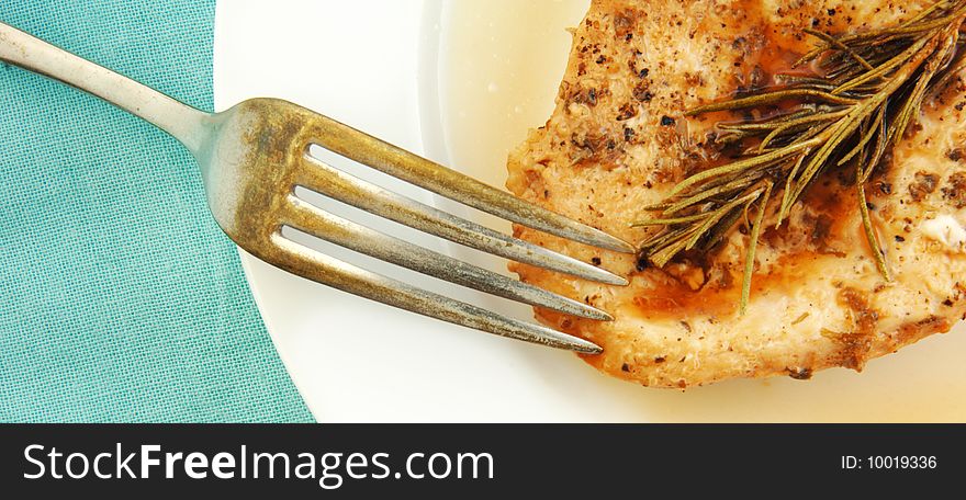 Rosemary chicken breast on a white plate with blue cloth background. Rosemary chicken breast on a white plate with blue cloth background.