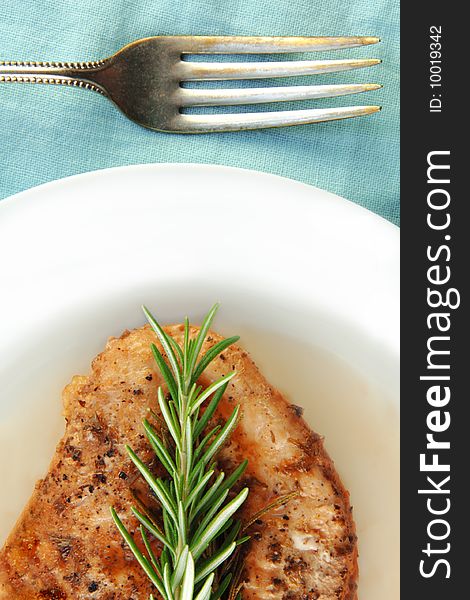 Rosemary chicken breast on a white plate with blue cloth background. Rosemary chicken breast on a white plate with blue cloth background.