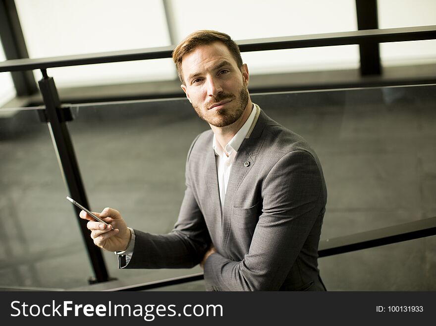 Portrait of happy smiling urban businessman using smart phone outside