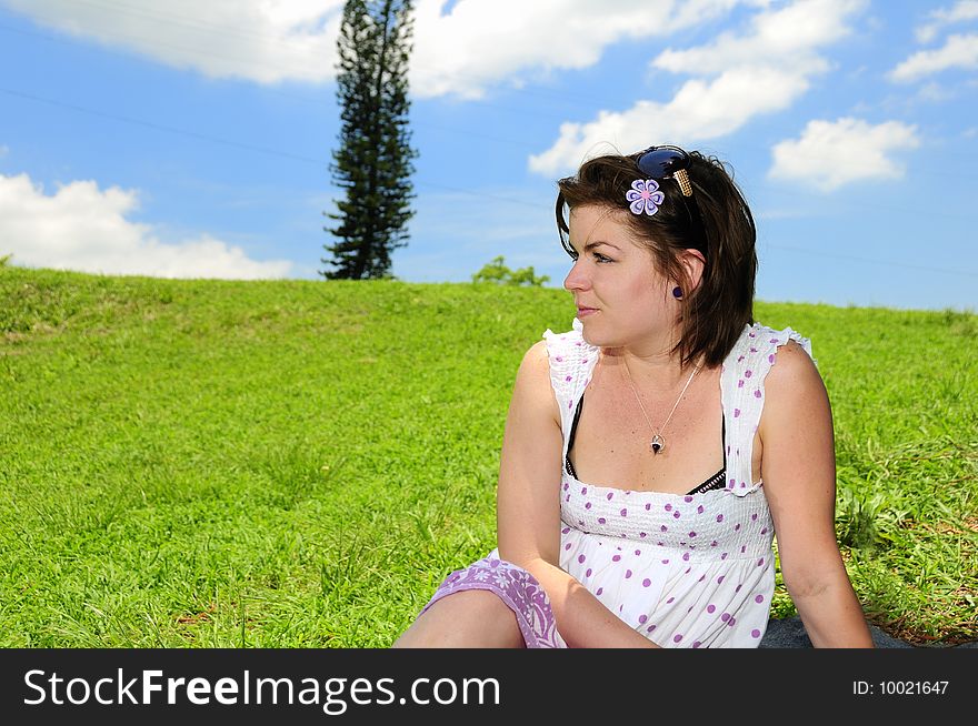 Portrait of young woman against green grass field and summer sky background. Portrait of young woman against green grass field and summer sky background