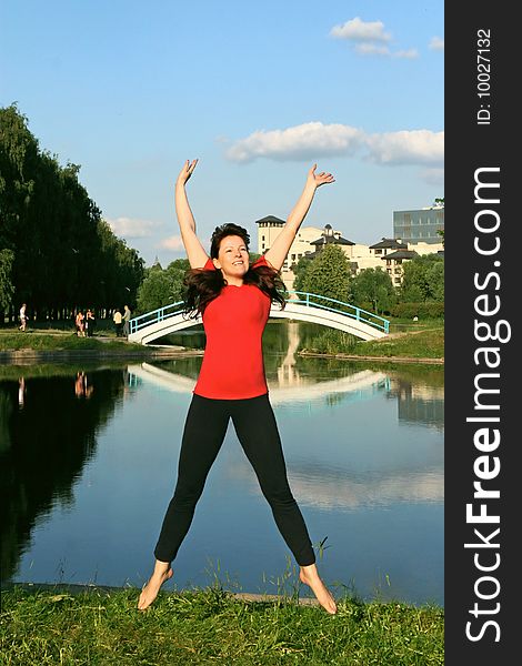 Beautiful young woman jumping with hands up outdoors.