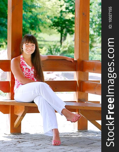 Attractive girl sitting on wooden bench in park