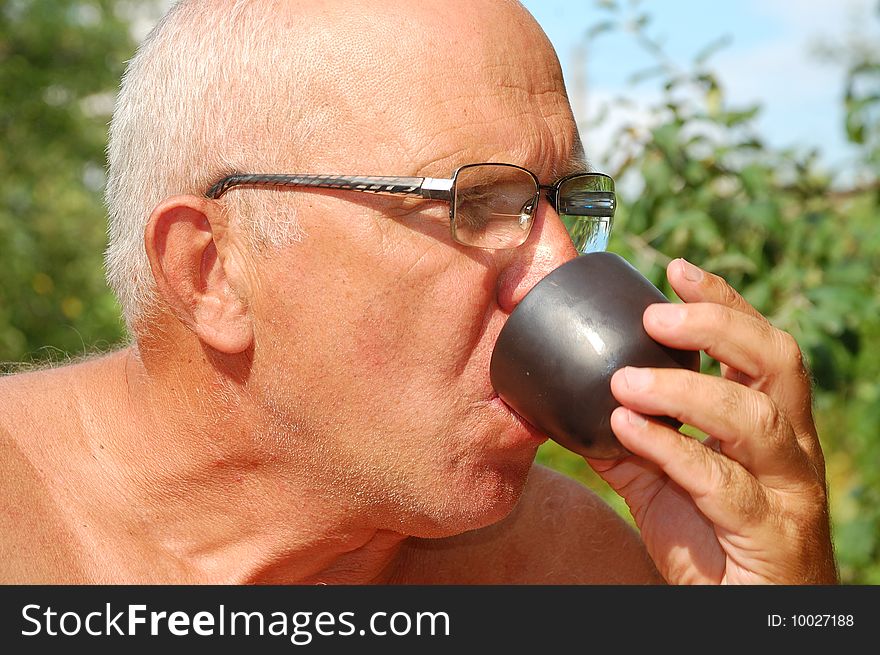 Senior man drinking  tea from Asian drinking bowl outdoor