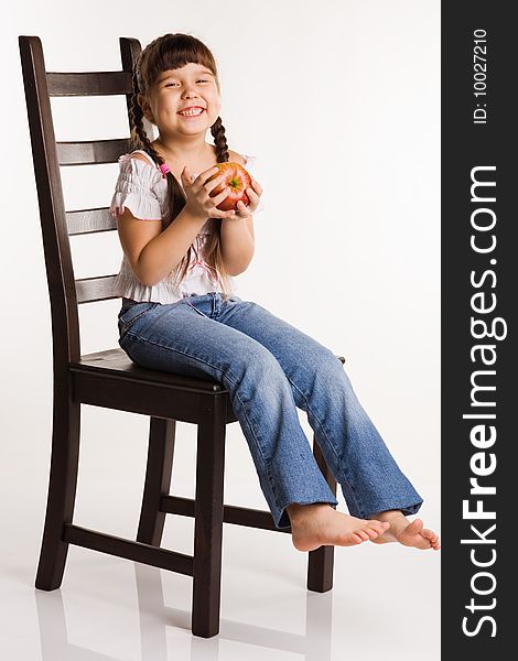 Photo of a girl with apple, sitting on a chair. Photo of a girl with apple, sitting on a chair