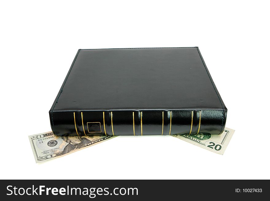Thick black book with golden trimming presses down twenty dollar bills isolated. Thick black book with golden trimming presses down twenty dollar bills isolated