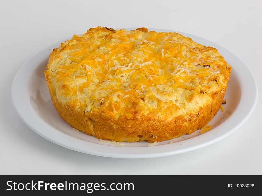 A round loaf of cheese bread on a plate; isolated on a white background.