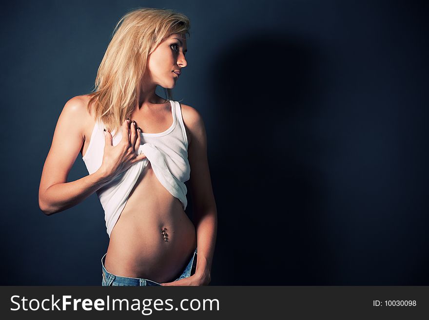 Portrait of attractive blond girl undress your shirt over dark with shadows. Portrait of attractive blond girl undress your shirt over dark with shadows