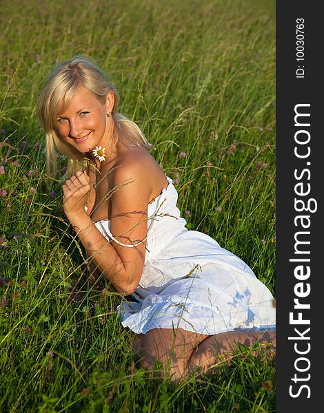 Young blond woman in white dress lying in grass. Young blond woman in white dress lying in grass