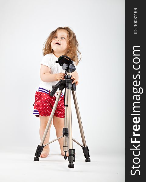 Little girl with tripod on gray background