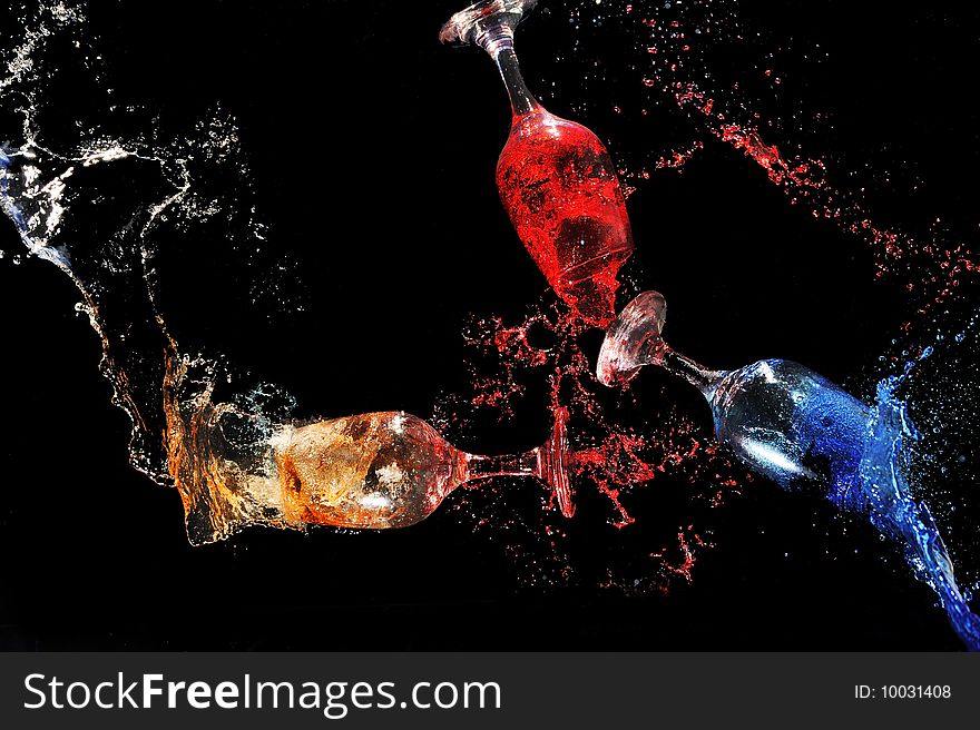 Colorful water splashing put of glasses in a black background. Colorful water splashing put of glasses in a black background
