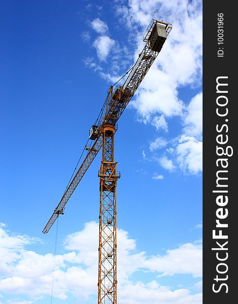 Photo of  two hoists at a construction site. blue sky with clouds.