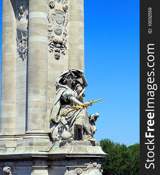 Parisian Statue in vertical orientation, with a blue sky background and green trees