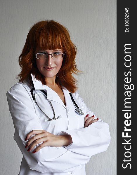 Young red-hair female medicine doctor isolated on grey background. Young red-hair female medicine doctor isolated on grey background