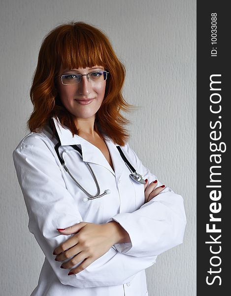 Young red-hair female medicine doctor isolated on grey background. Young red-hair female medicine doctor isolated on grey background