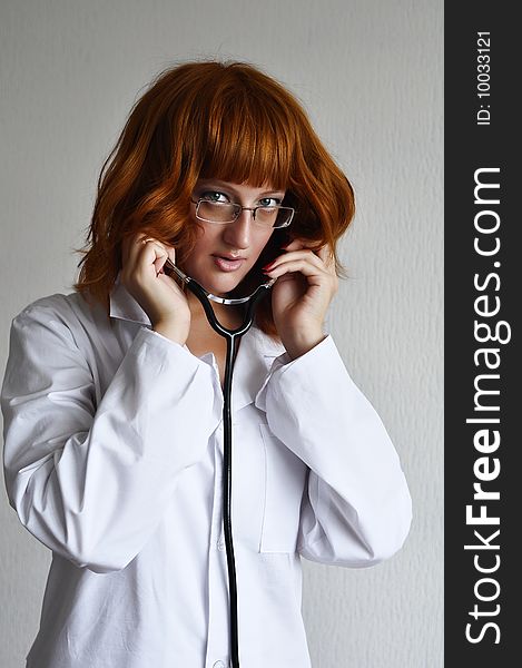 Young red-hair female medicine doctor isolated on grey background. Young red-hair female medicine doctor isolated on grey background