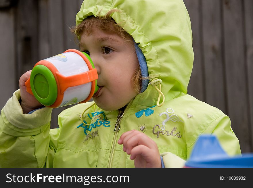 Little girl drinking in the garden