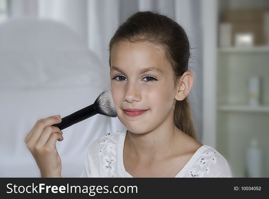 Pretty girl make up her self with brush and powder in white room