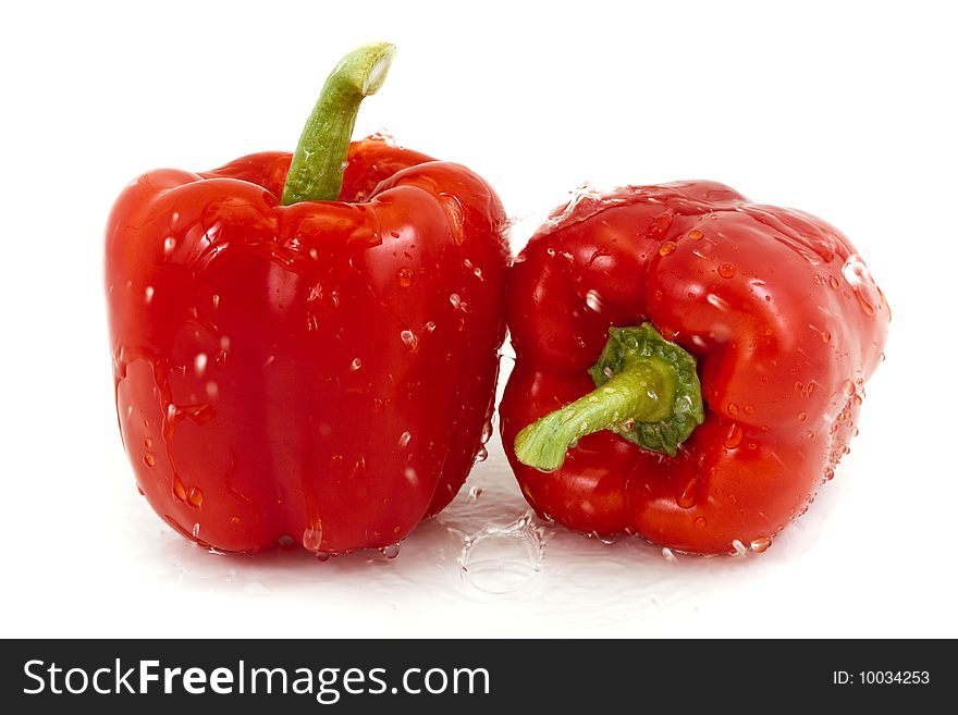 Two red peppers with droplets on a white background