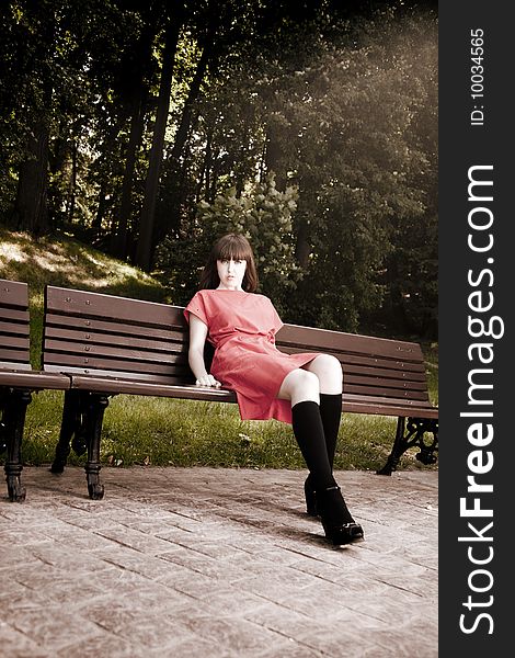 Beauty Woman Sitting On A Park Bench Under the Sunlight