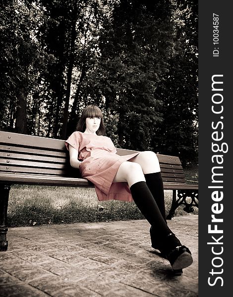 Pretty Woman Sitting On A Bench. Retro Styled Photo.