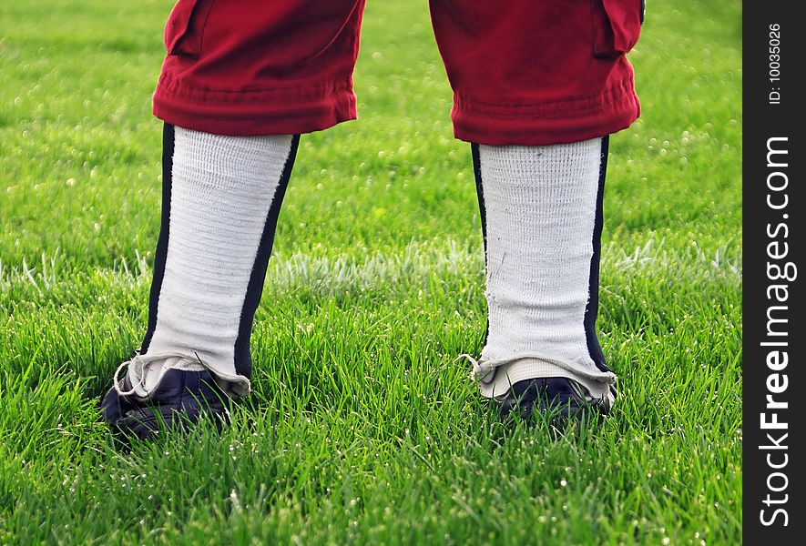 Young soccer player waits patiently to enter the game, detail view from the knees down. Young soccer player waits patiently to enter the game, detail view from the knees down