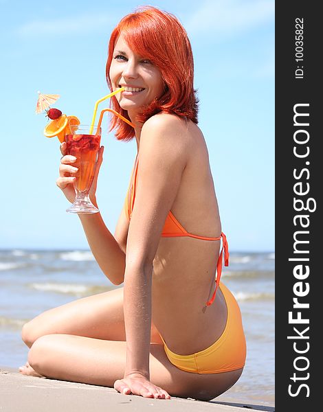 Young woman with fruit cocktail relaxing on beach. Young woman with fruit cocktail relaxing on beach