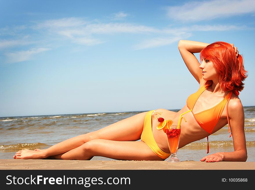 Young woman with fruit cocktail relaxing on beach. Young woman with fruit cocktail relaxing on beach
