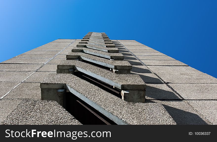 Facade of a building with balconies in the perspective on a background of the blue sky. Facade of a building with balconies in the perspective on a background of the blue sky