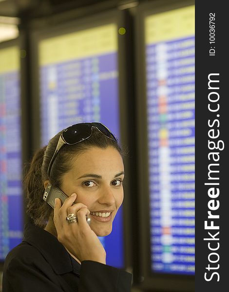 Airport Woman with cellphone in front of a timetable