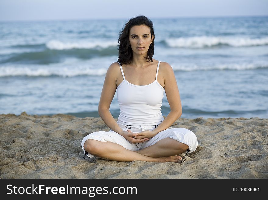 Woman in white making yoga exercise on the beach. Woman in white making yoga exercise on the beach