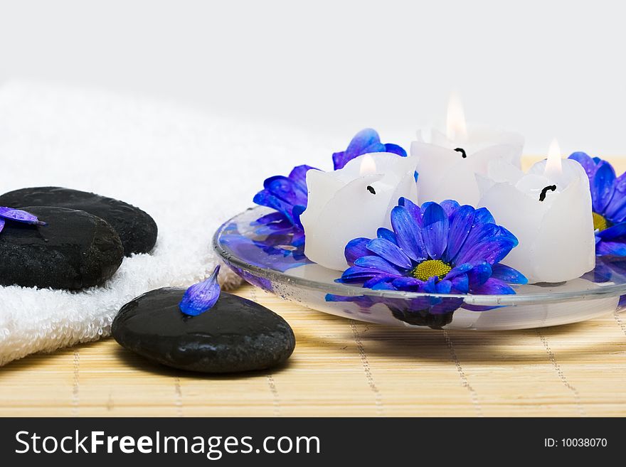 Candles in water with blue flowers and towel