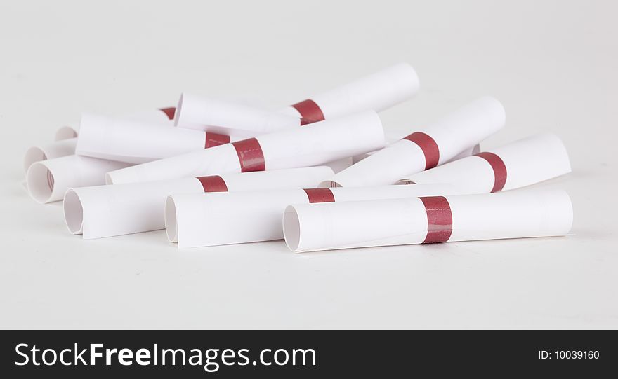 A loose pile of small rolled up messages, individually sealed with a brown tape band; isolated on a white background. A loose pile of small rolled up messages, individually sealed with a brown tape band; isolated on a white background.